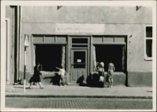 [Przed witryną sklepową na ulicy Ratuszowej w Mrągowie]